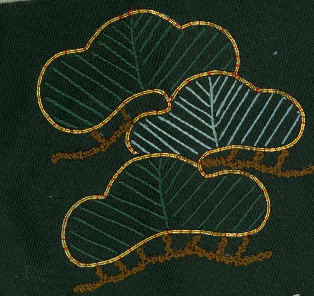 Embroidered green leaves with golden outline on dark fabric