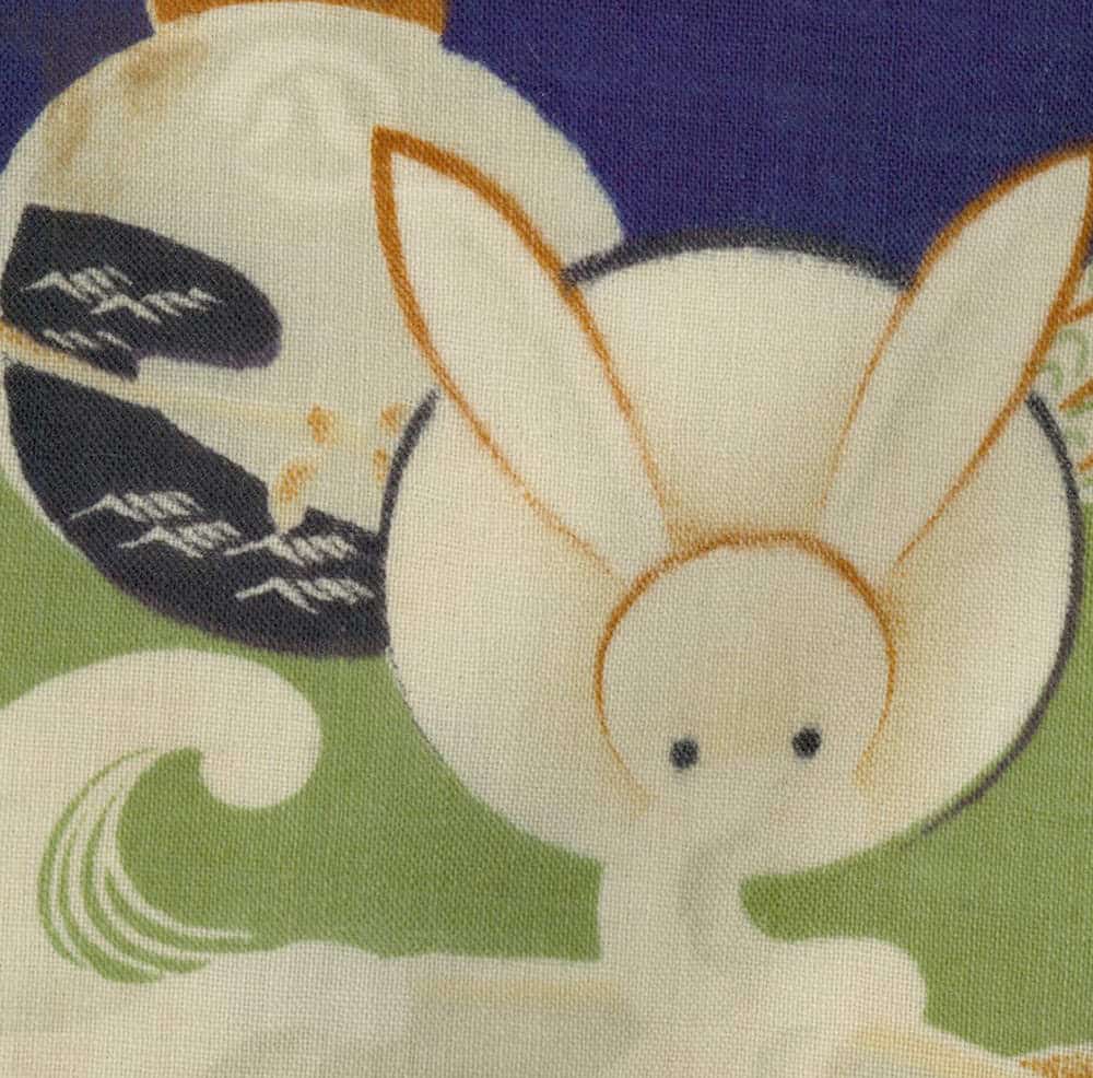 Stylized cartoon bunny with large eyes on colorful fabric background