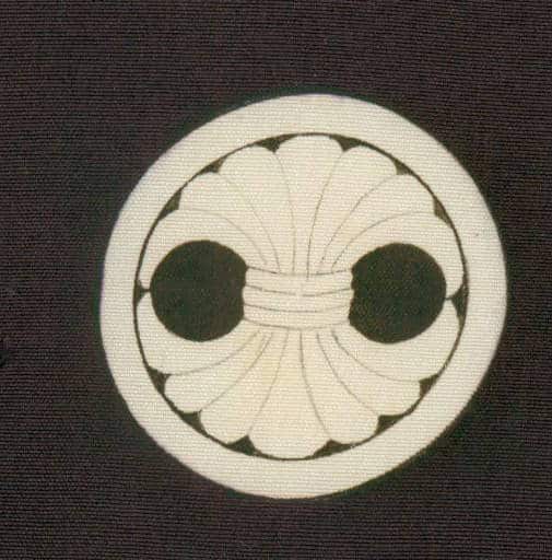 Stylized white circular emblem with two black circles and radial design