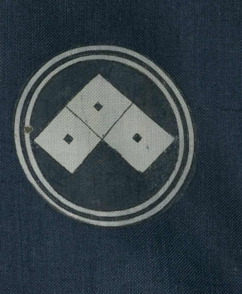 Geometric logo with four-part square inside circular border on dark fabric