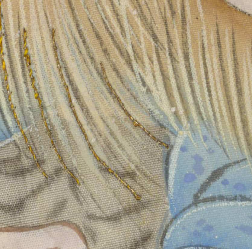 Detailed embroidery with golden threads on textured fabric with blue accents