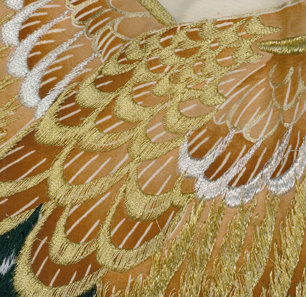 Intricate golden and silver embroidered feather-like pattern on fabric