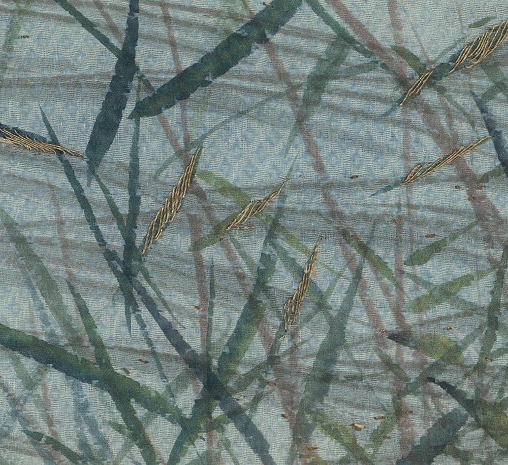 Intricate tree branches and golden threads on textured blue-green fabric