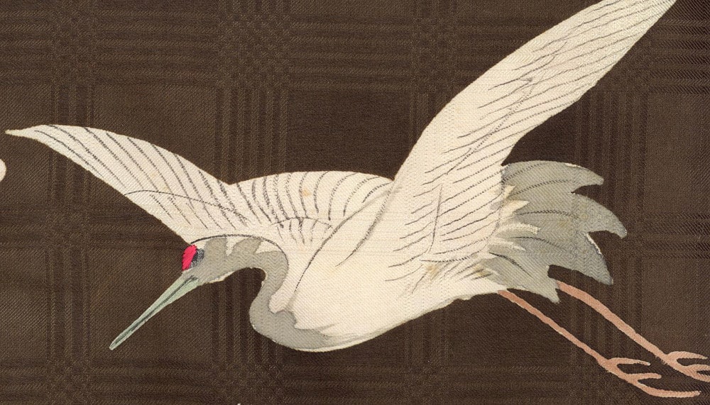 White crane in flight with extended wings against a brown background