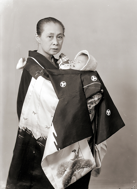 Older woman in traditional Japanese kimono carrying a baby