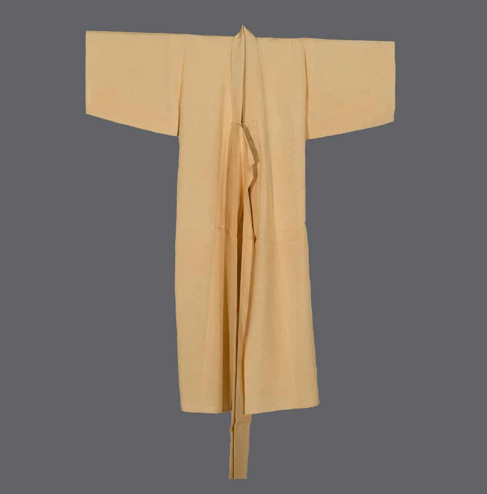 Pale yellow Japanese kimono with wide sleeves, hanging against gray background
