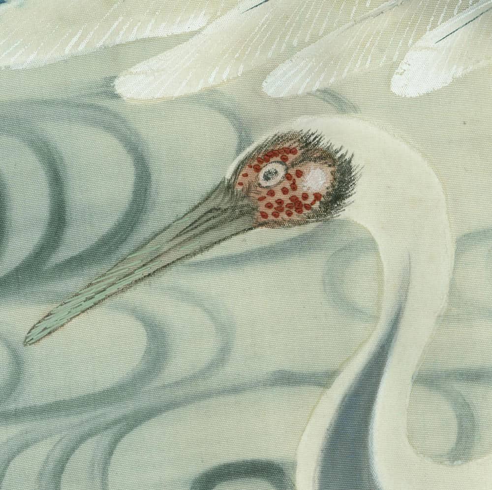 White crane with vibrant red marking on head and eye