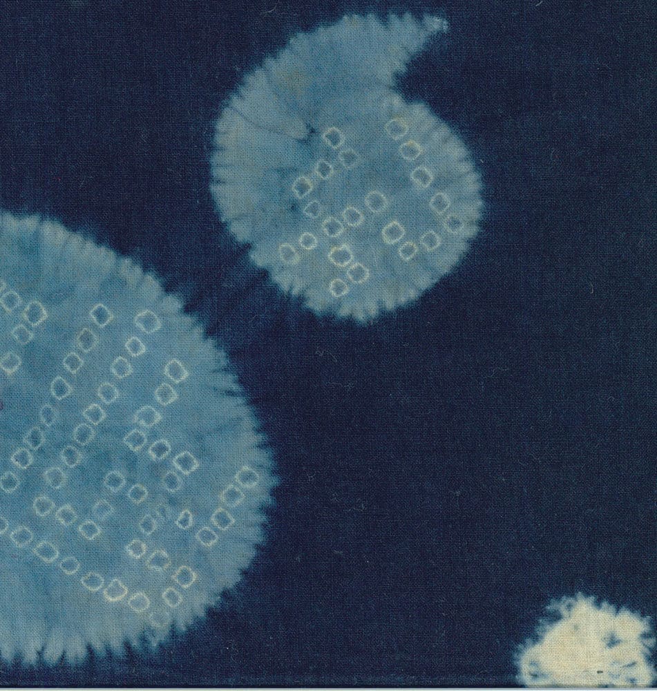 Blue shibori fabric with circular tie-dye patterns and geometric shapes