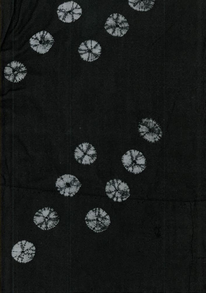 Black fabric with white tie-dye circular patterns scattered across surface