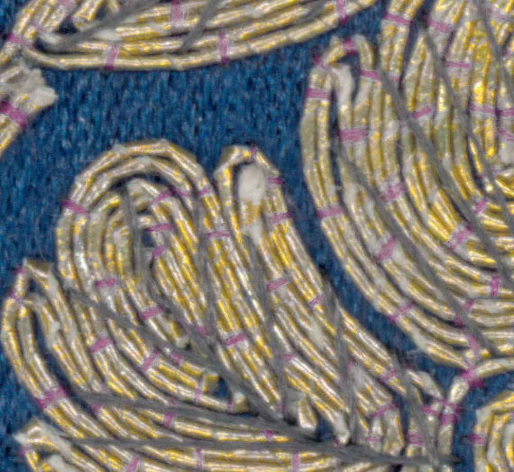 Embroidered textile with gold and silver threads on blue background