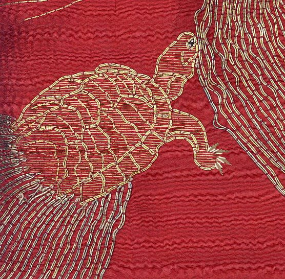 Golden turtle embroidered on vibrant red textured fabric background