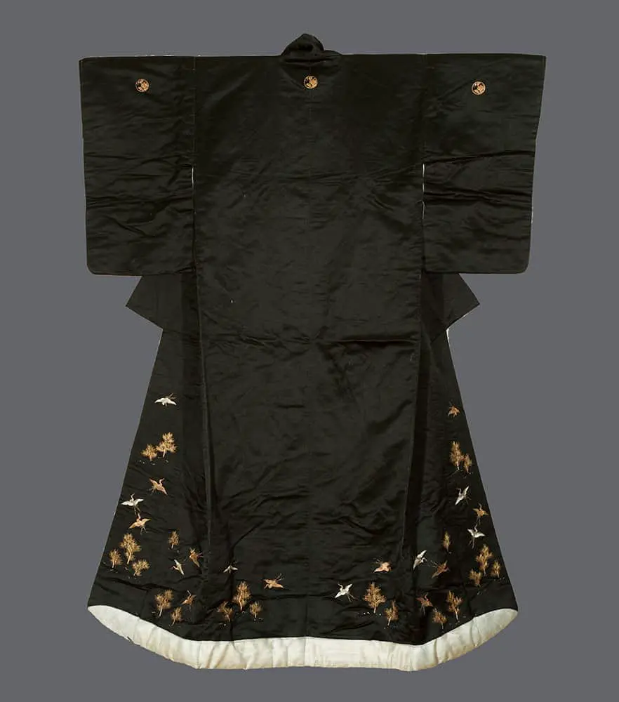 Meiji black shusu‑silk uchikake with metallic‑embroidered white cranes, golden‑accented pines, circular mon, and bluish‑grey rinzu lining emphasizing refined restraint