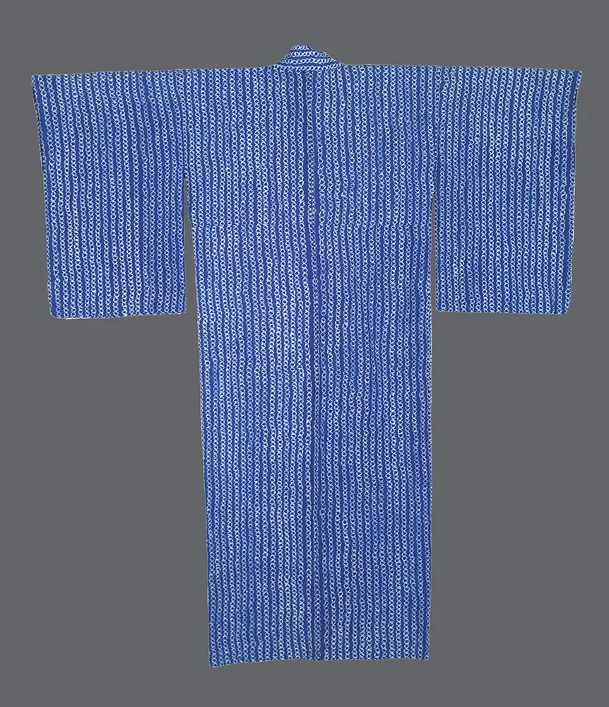 Cotton shibori yukata with vertical white linked‑chain or wave motifs on a vibrant blue ground showing irregular textured resist lines 