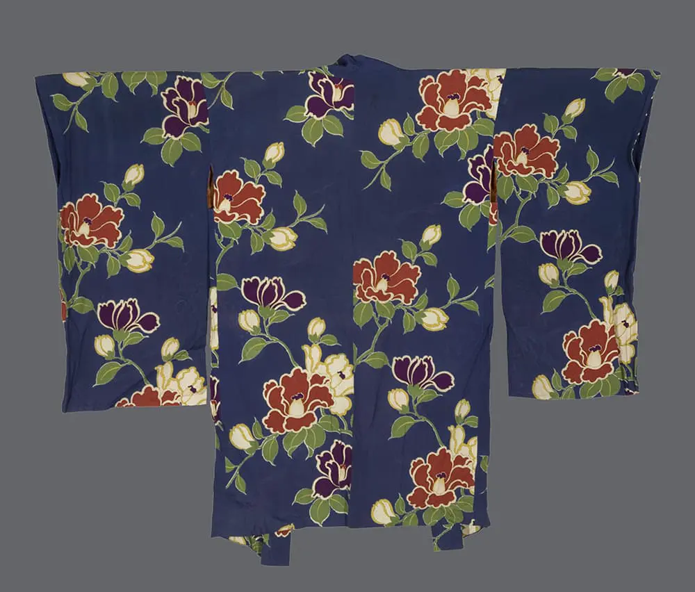 Taishō rinzu haori with kata‑yuzen camellias in coral, burgundy, and cream with glossy green leaves scattered asymmetrically across a deep indigo ground 