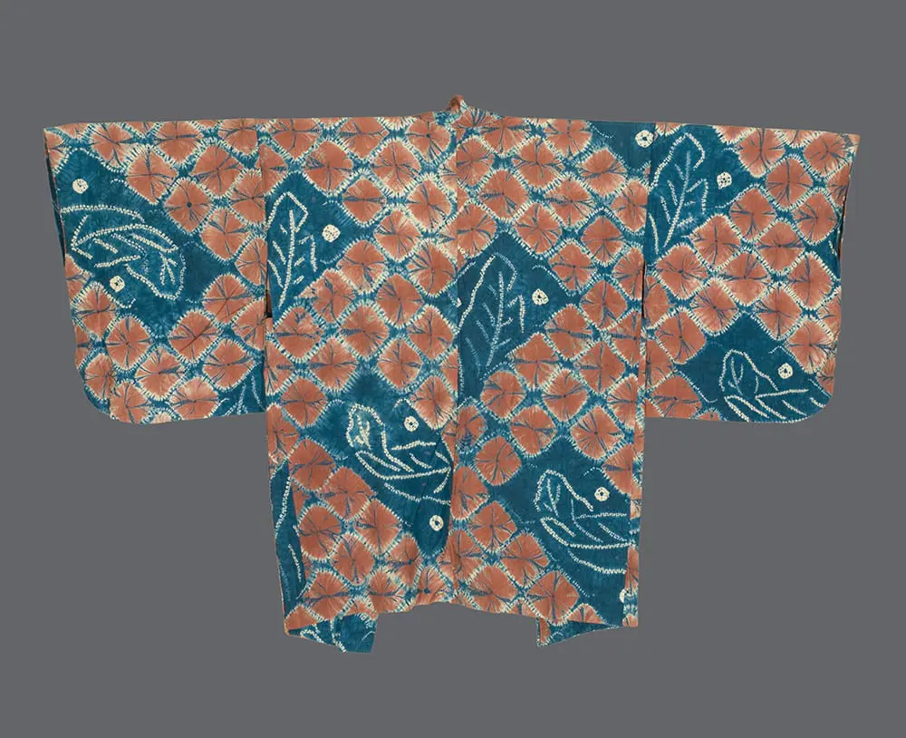 Shibori silk haori with coral‑orange lozenge lattice sections alternating with deep indigo panels of white resist‑dyed leaf motifs and dotted accents 