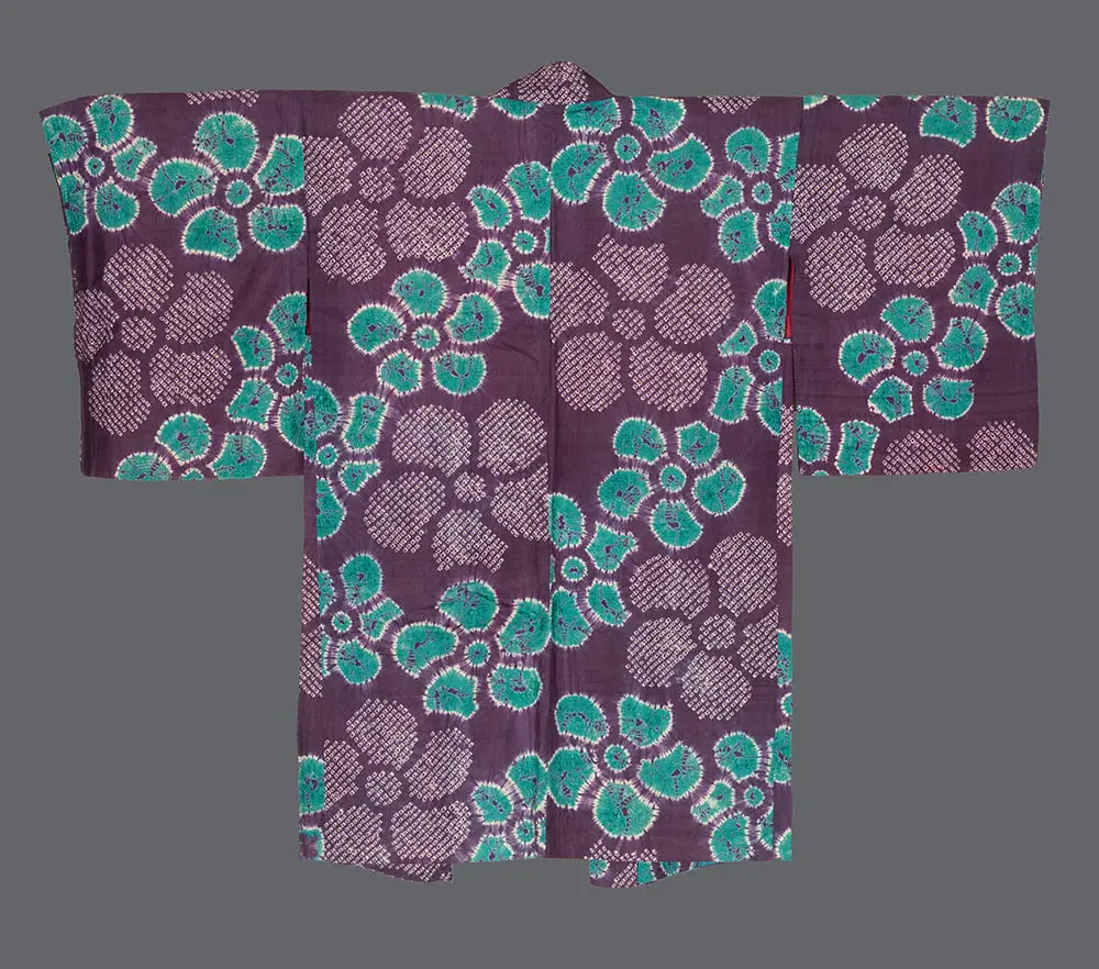 Shibori silk haori with vibrant turquoise‑green nejiumo plum blossoms and pink‑and‑white crosshatched circles on a deep eggplant ground with crisp resist details 