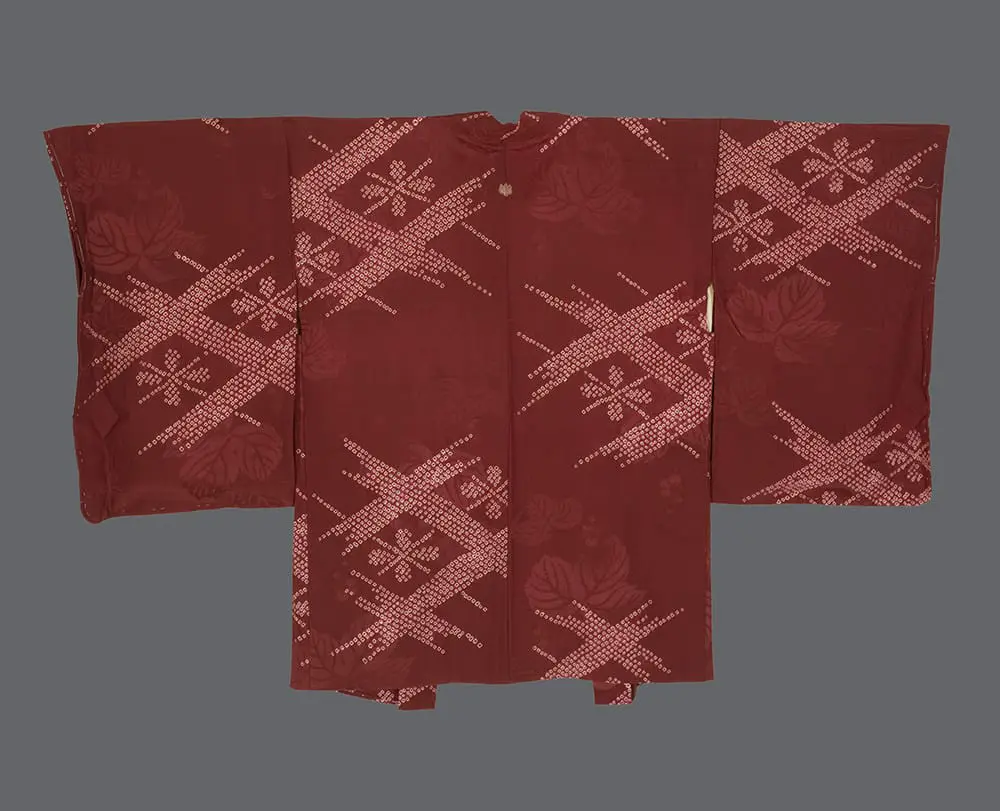 Terracotta-red rinzu silk haori featuring large white shibori geometric lattice patterns and tonal woven ivy leaves.