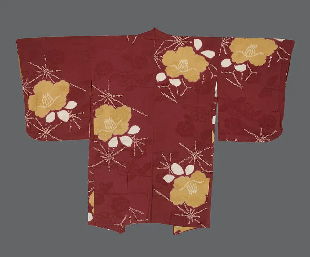 Burgundy rinzu silk haori with large ochre-yellow shibori camellia flowers and white dotted starburst patterns.