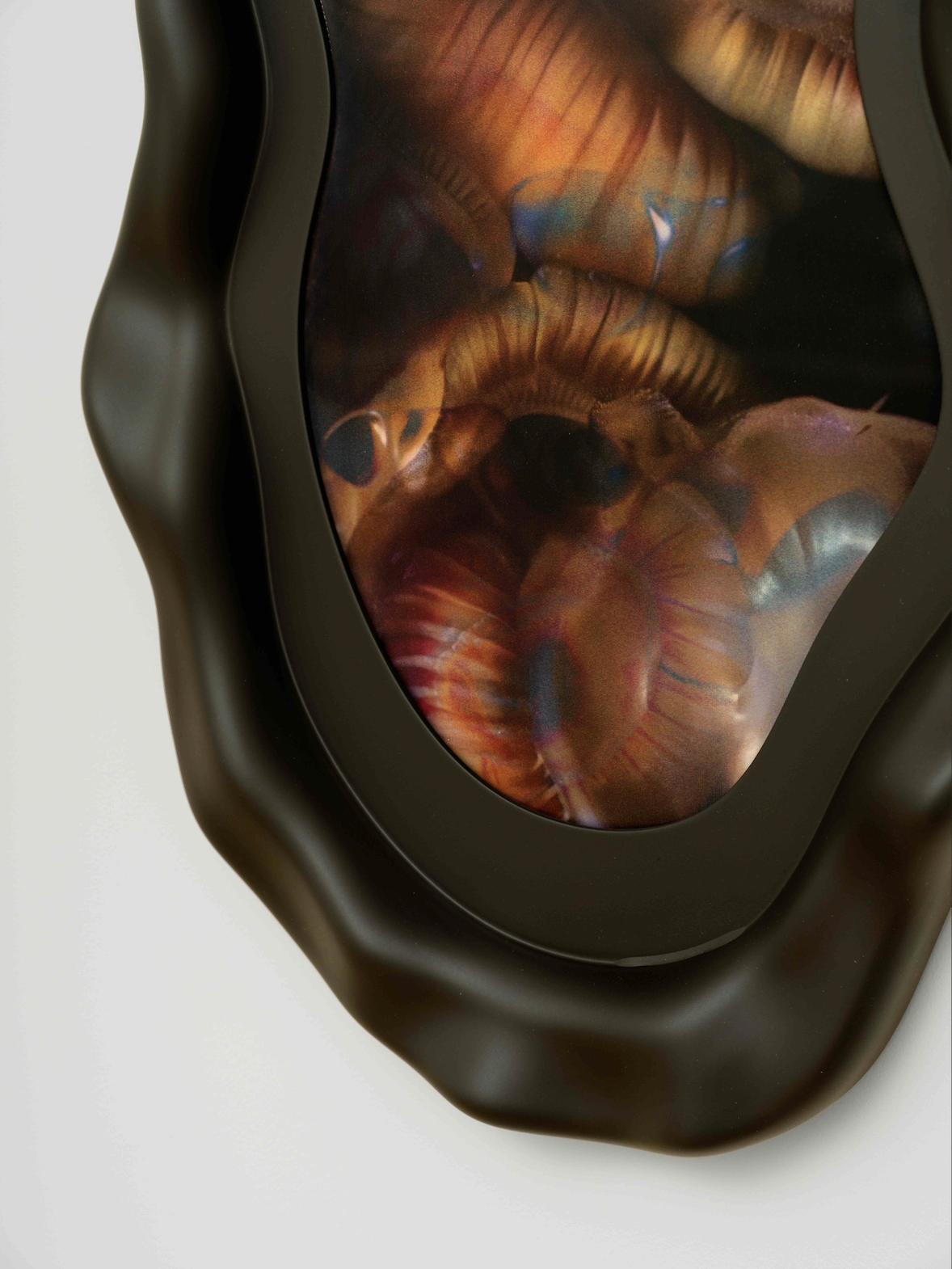 A detail shot of a lenticular art print in an organic black frame on a white wall. 