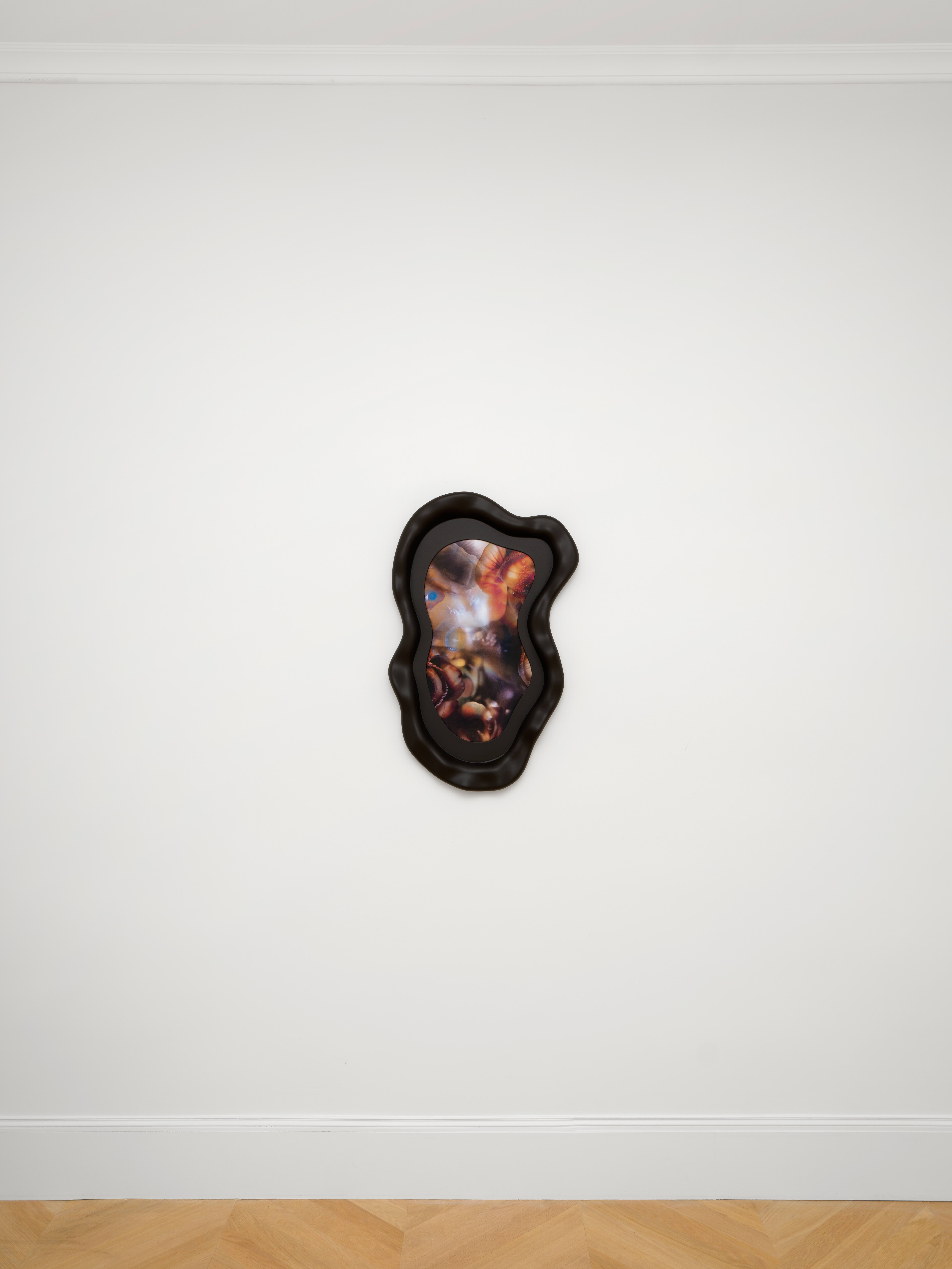 A lenticular art print in an organic black frame on a white wall. 