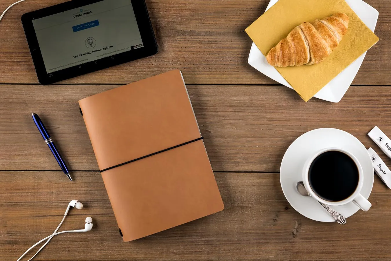 Lifestyle photography of a branded coffee mug and notebook on a wooden desk, illustrating consistent brand touchpoints for small businesses.