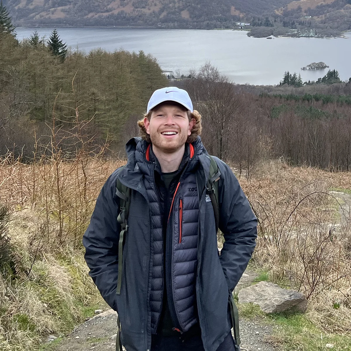 Man smiling in front of a lake and mountains
