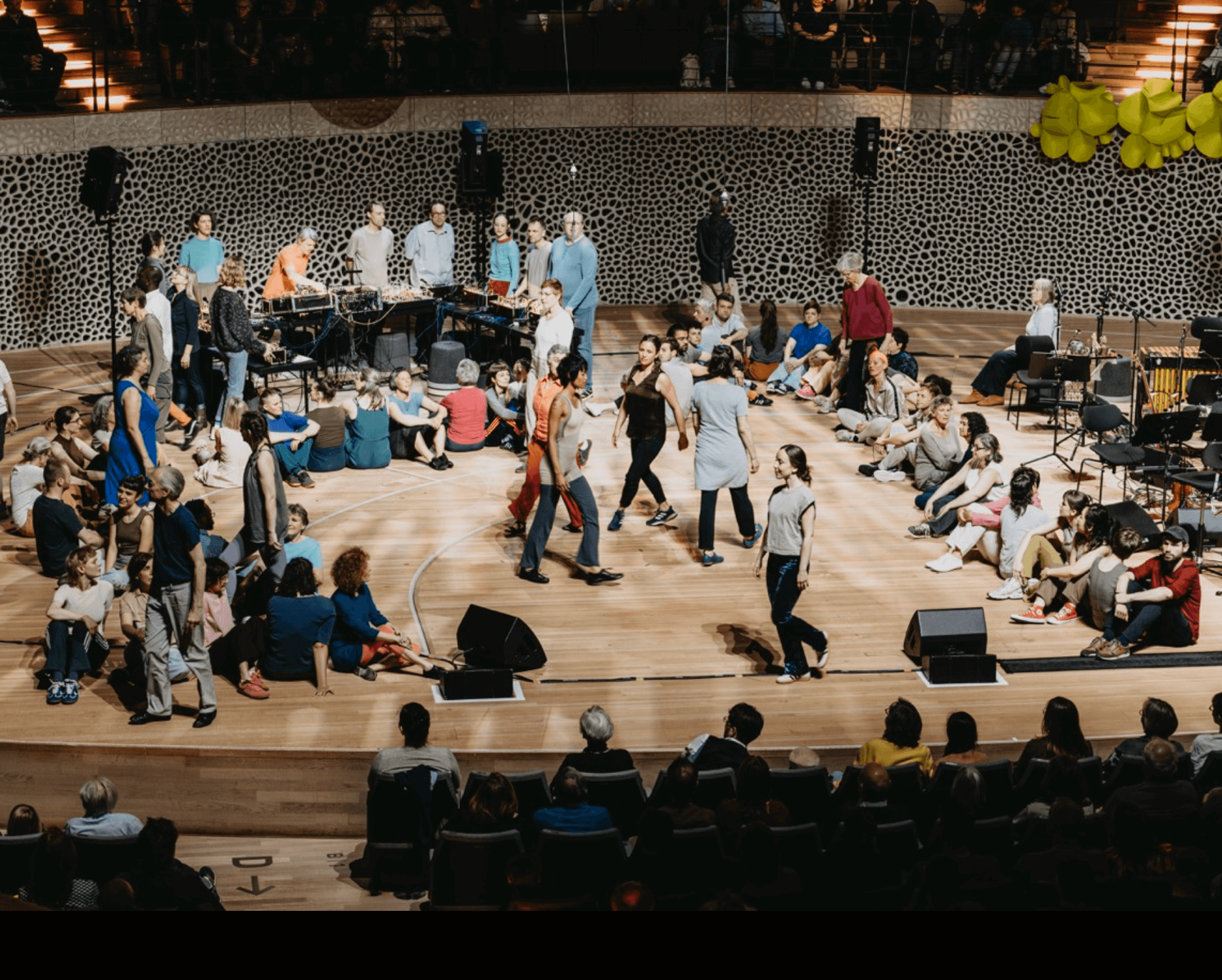 Many people sitting and walking at a stage.