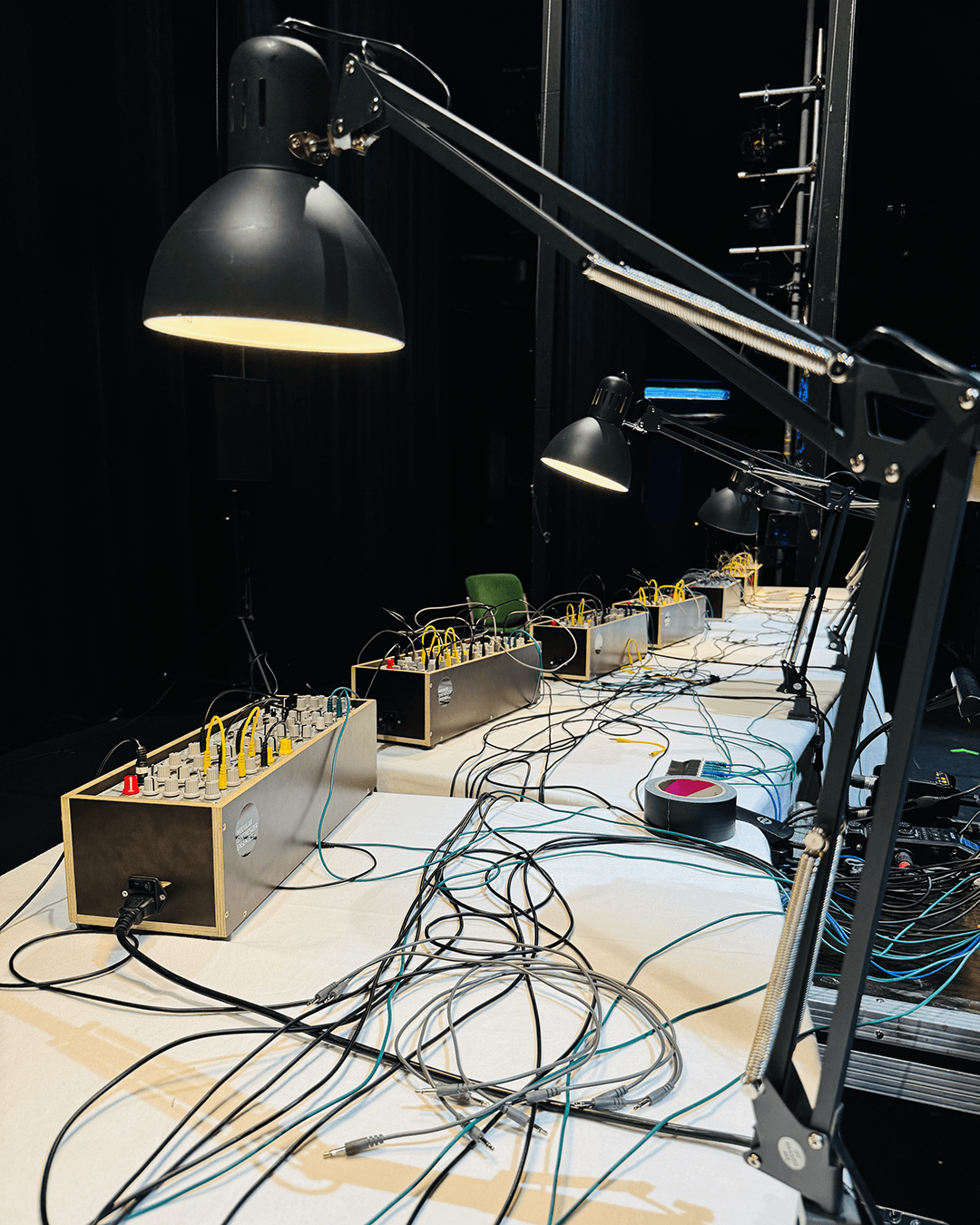 six modular synthesizer at a table with many cabels and lamps.