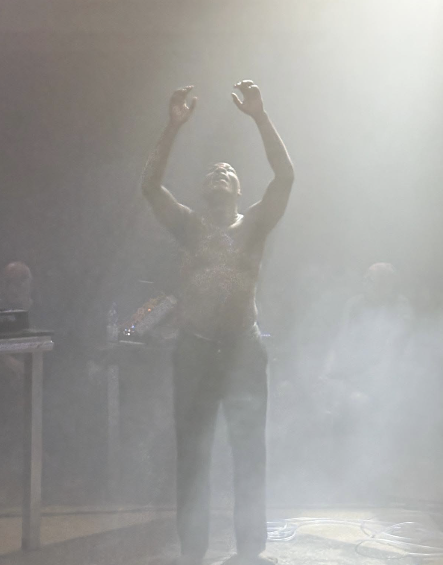 Performer still in a room with light and smoke