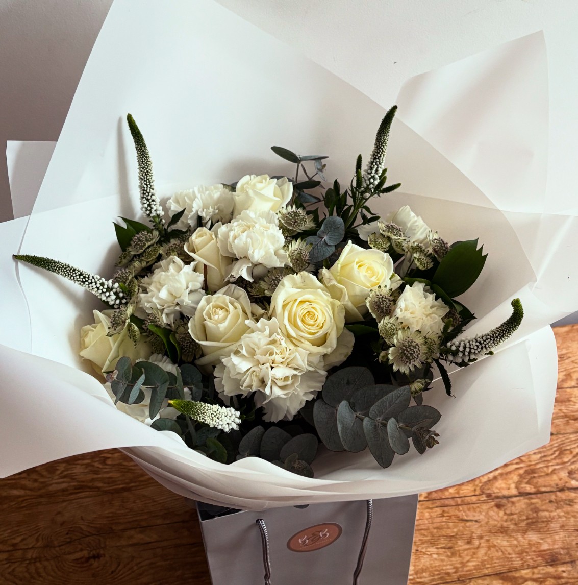 Rhea is a wonderful combination of the purest white roses, astrantia, veronica and cream carnations, with mixed foliages.
