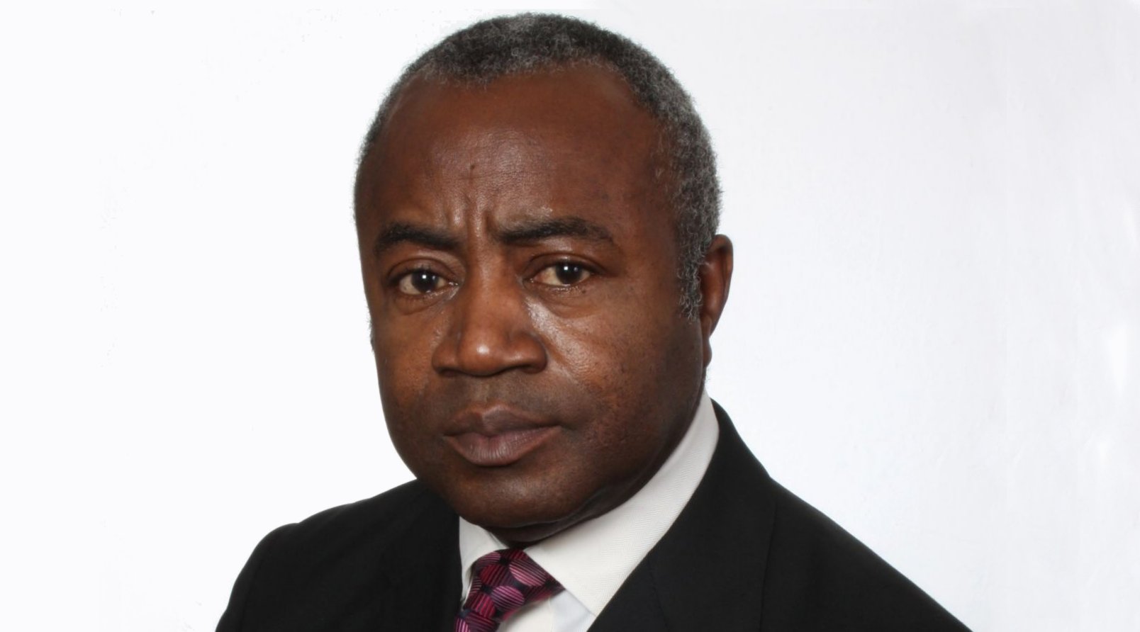 Photograph of Courtenay Griffiths (headshot) in a black blazer, white shirt and red and black decorative tie.