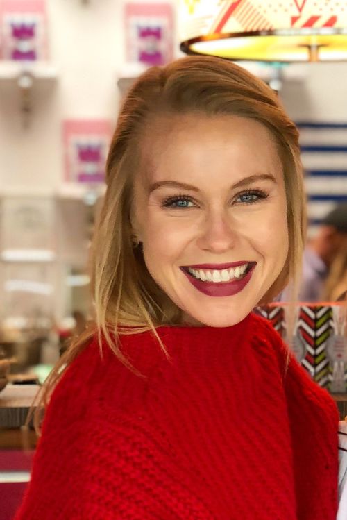 woman smiling brightly at camera and wearing a red top