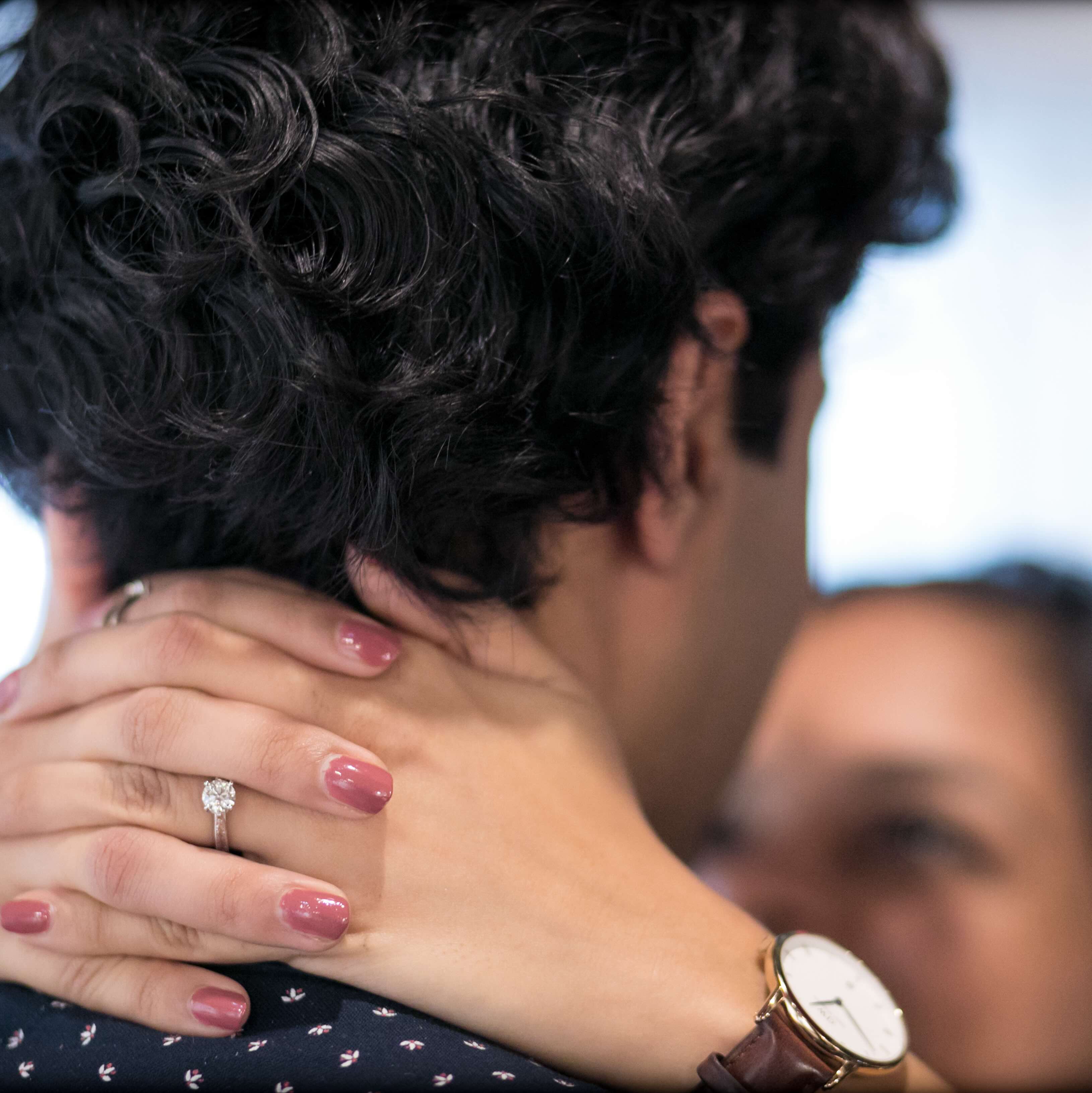 closeup of woman's hands around the back of her partner's neck, focusing on the back of the man's head