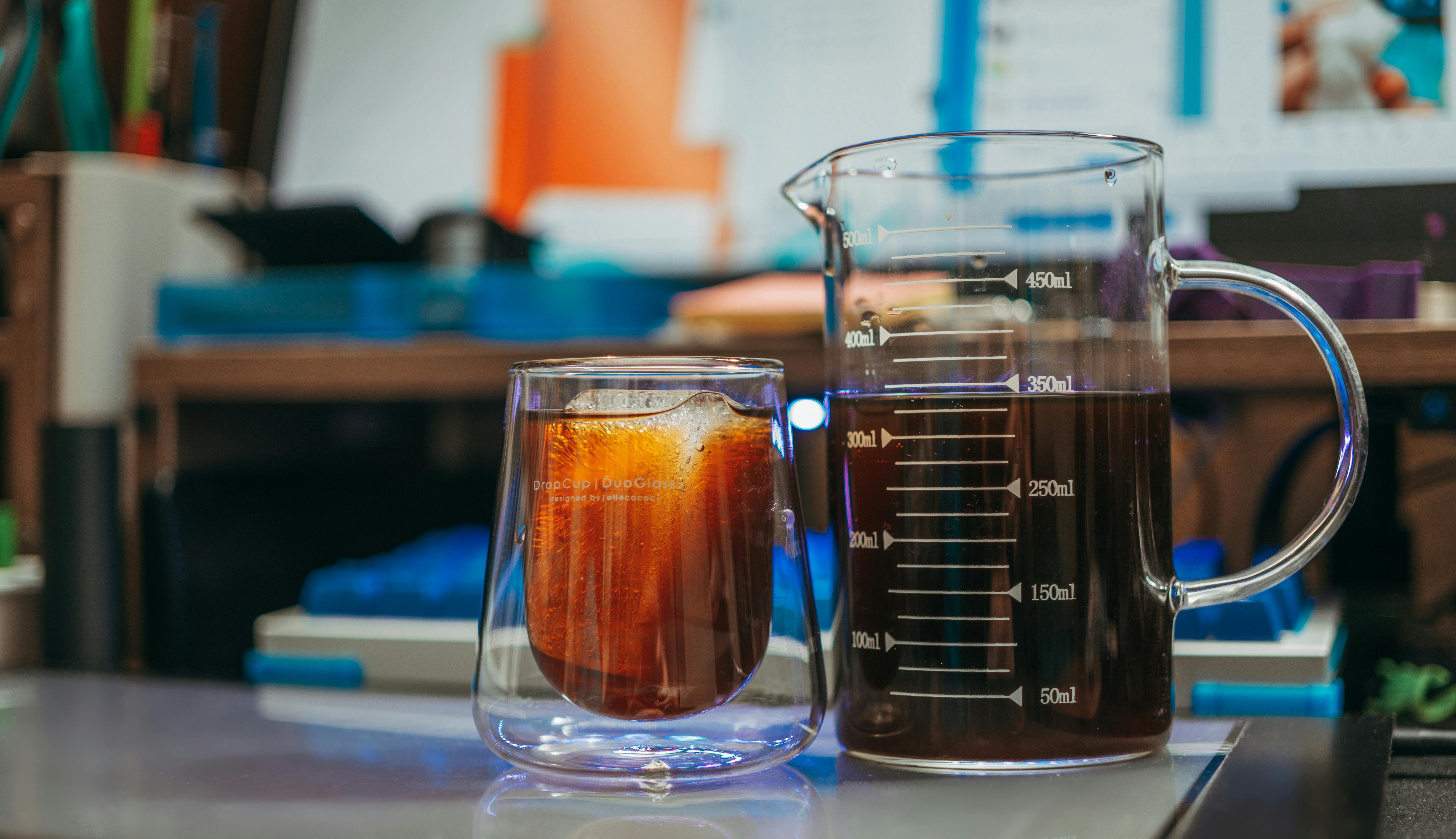 A close-up shot of iced coffee and a measuring beaker on a desk, perfect for coffee enthusiasts.