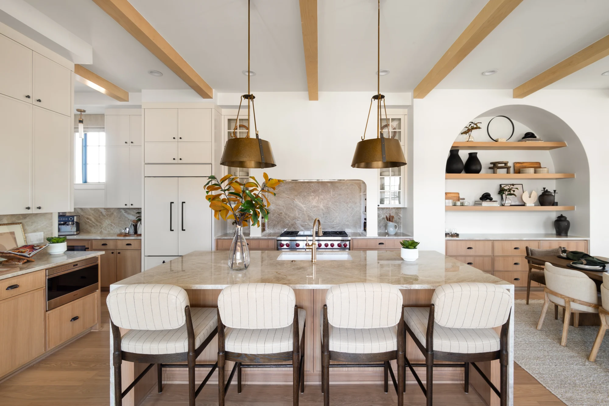 Light-filled kitchen with a stone island, wood ceiling beams, and pendant lighting at The Villas at Lakeside