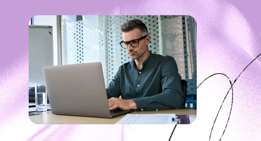 Man working on a laptop at an office desk.