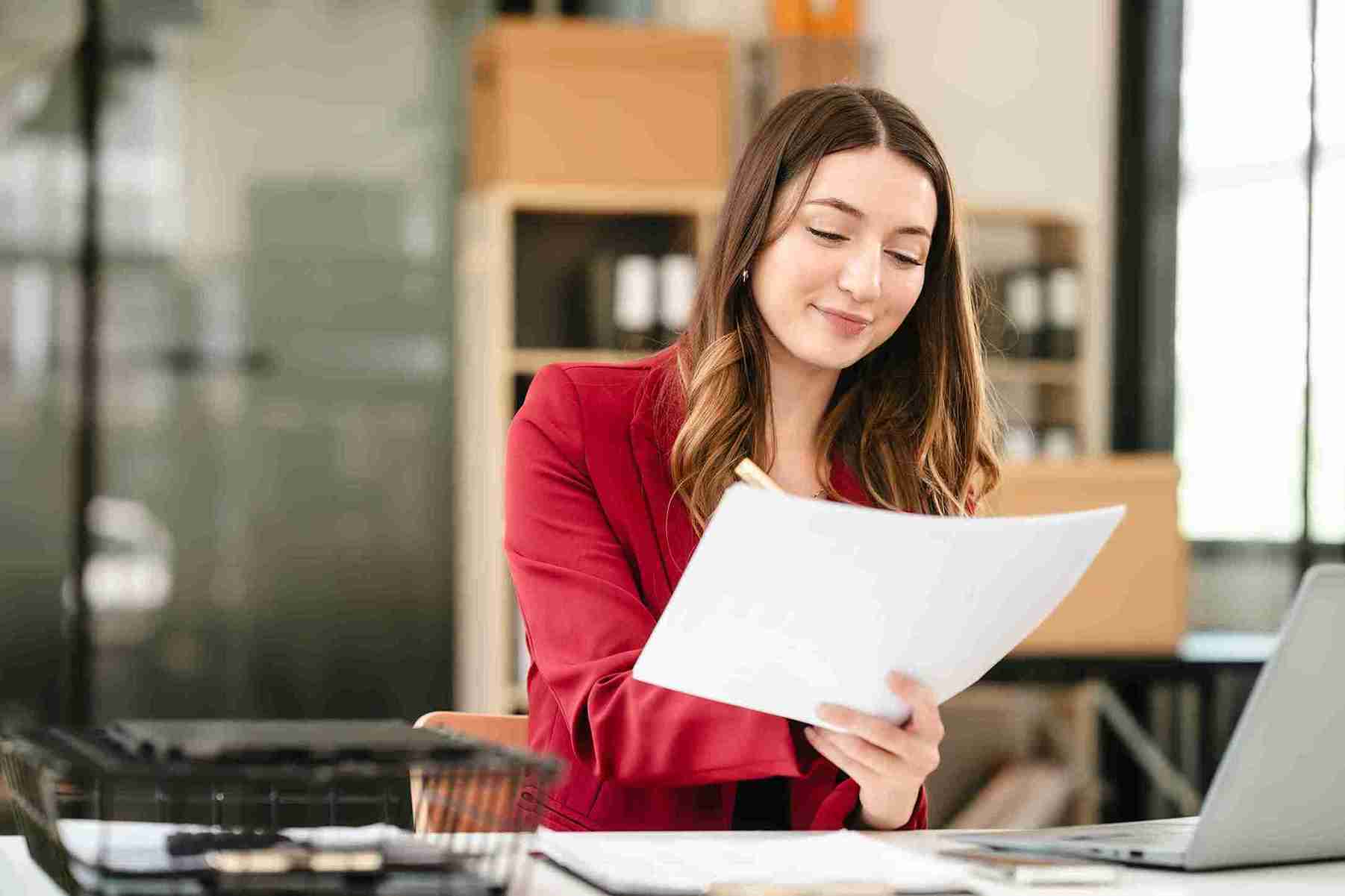 Image of a happy woman at her work looking at some papers.