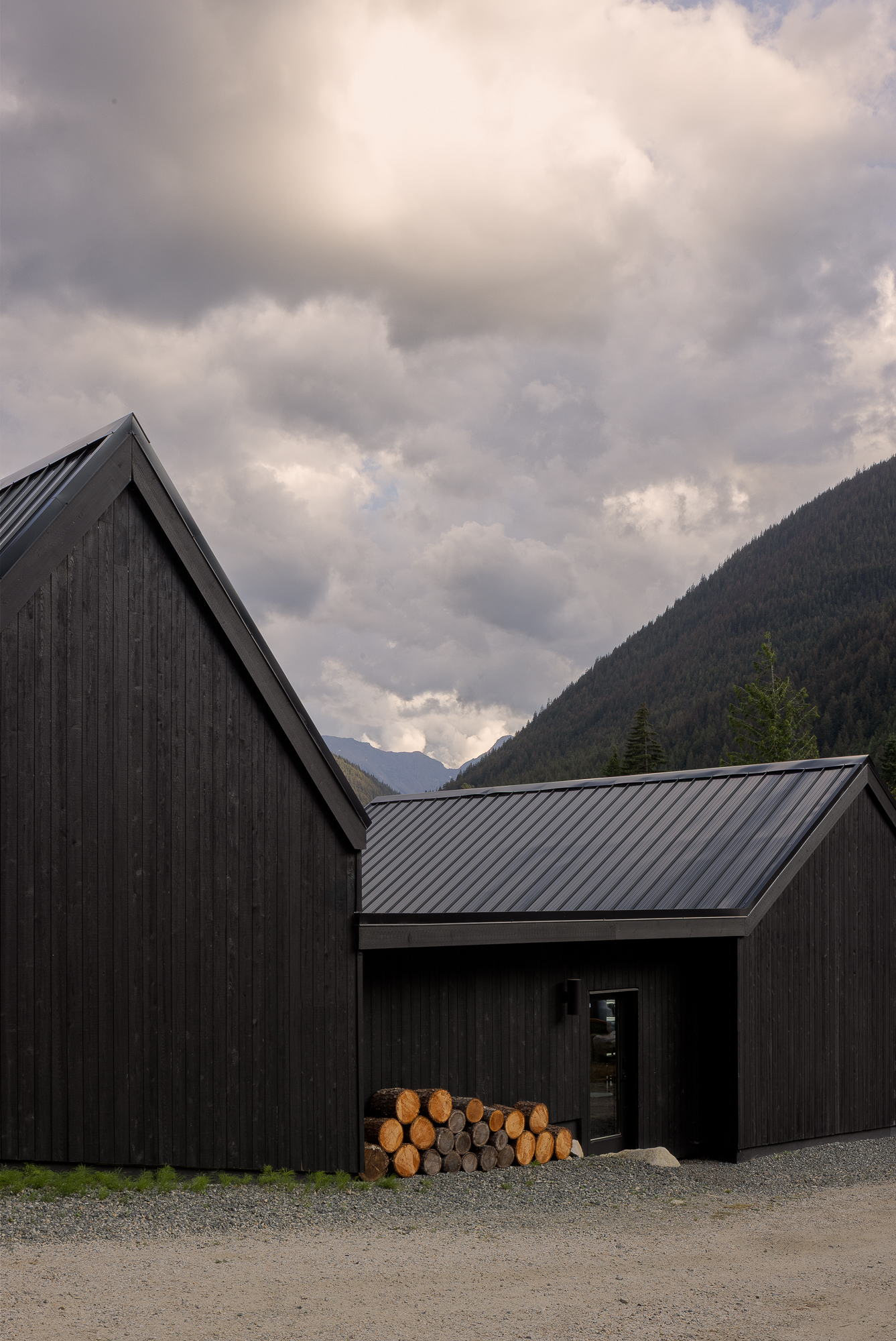 exterior view of dark wood building with pitched roof and entry