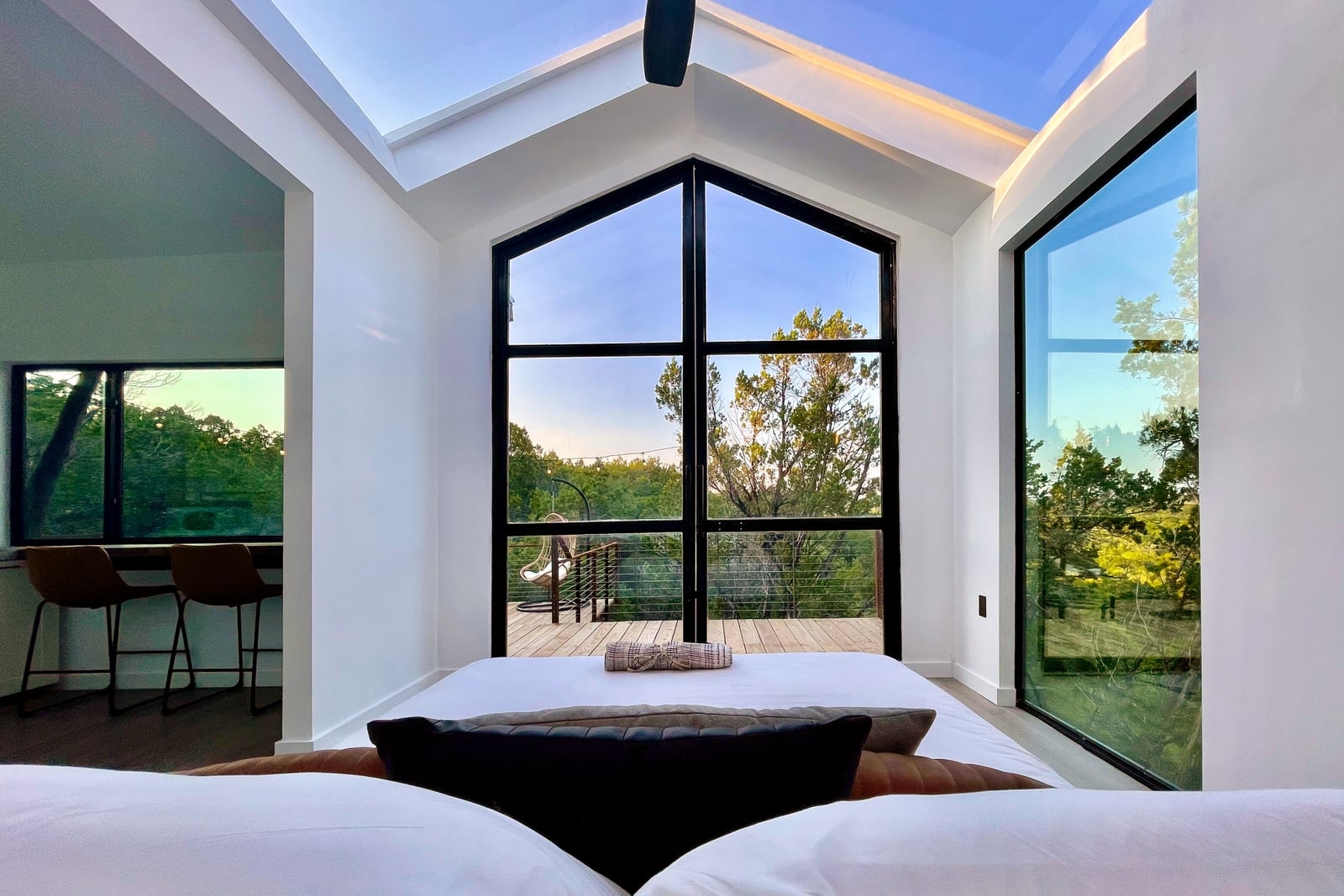 The bedroom at Yoku, with the glass roof over the bed and the trees outside