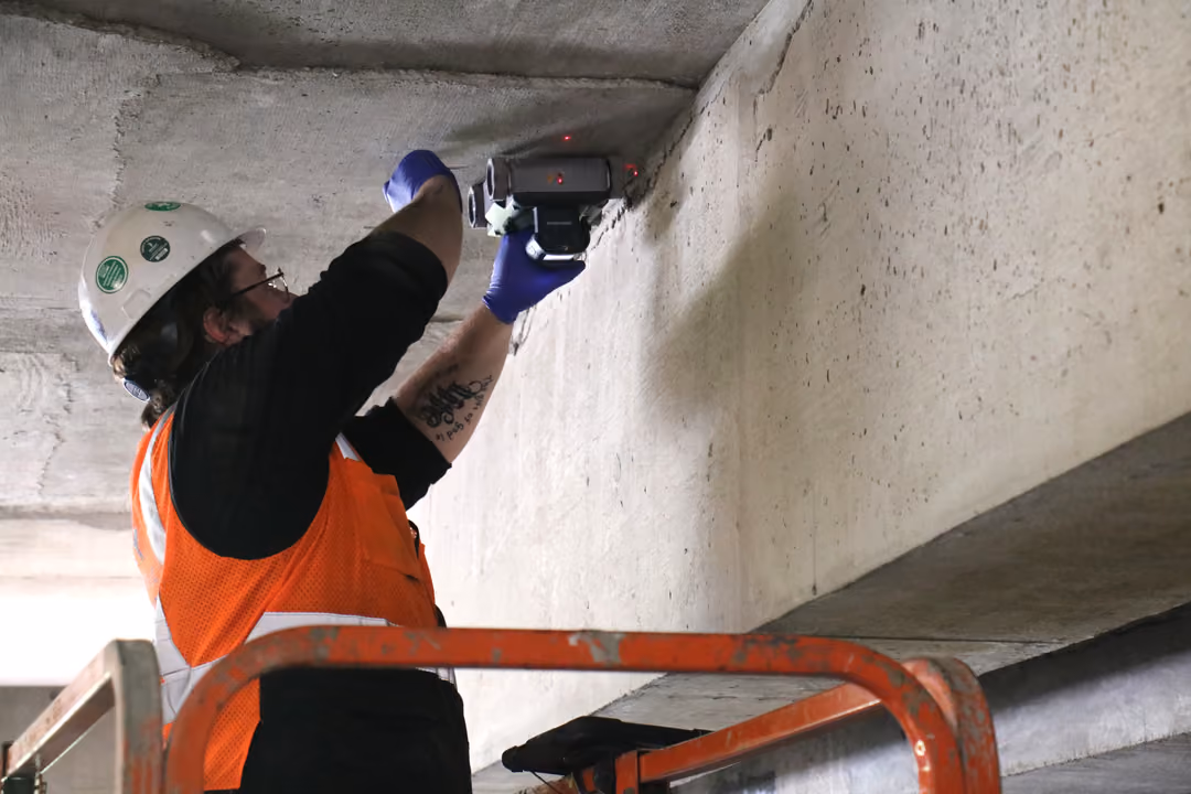An image of a Trinity Subsurface technician scanning a parking garage ceiling on a lift.
