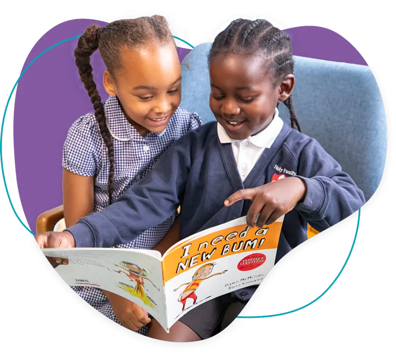 Two young girls sitting together, smiling and reading the book 'I Need a New Bum!'