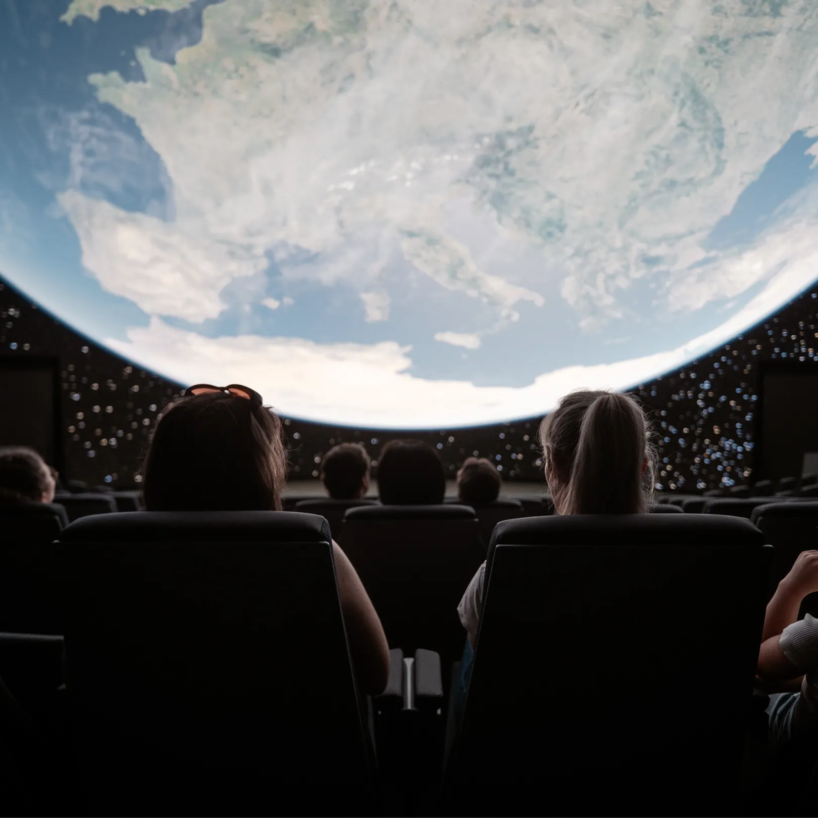 Visitors watching a projection of Earth in the dome of the planetarium.