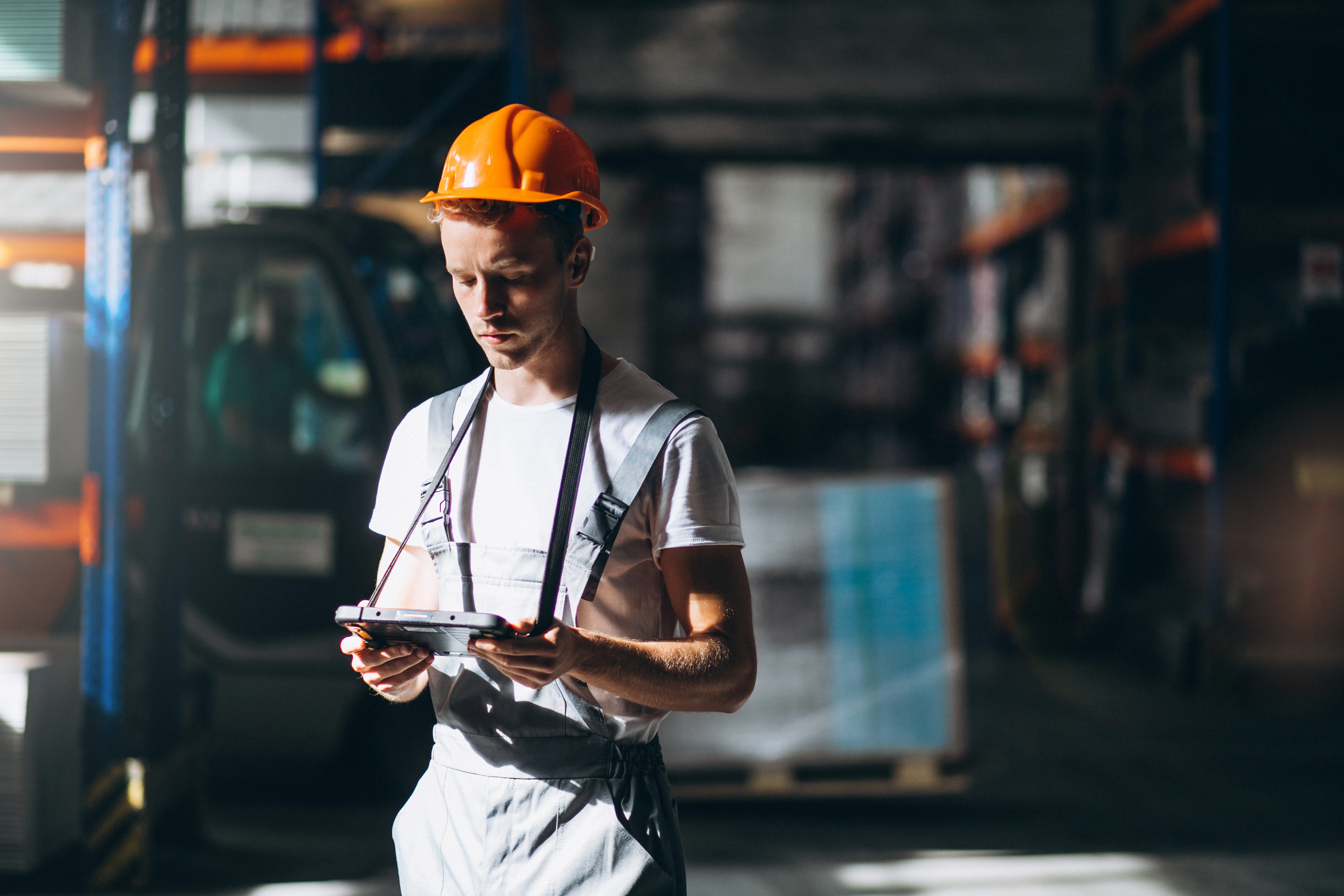 Technician with Hard Hat holding tablet reviewing inventory.