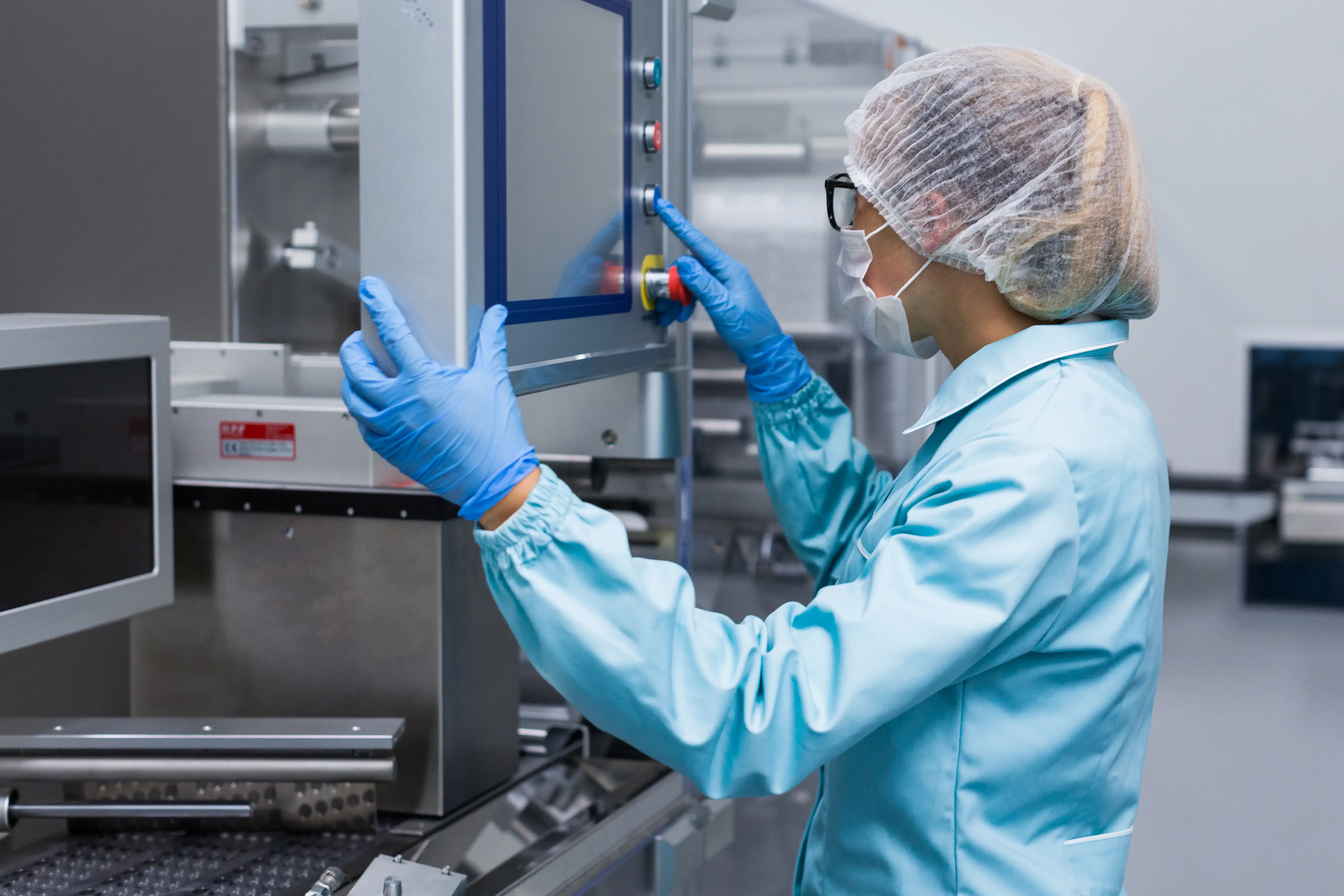 Biomedical Technician working in lab wearing full lab gear and hairnet.