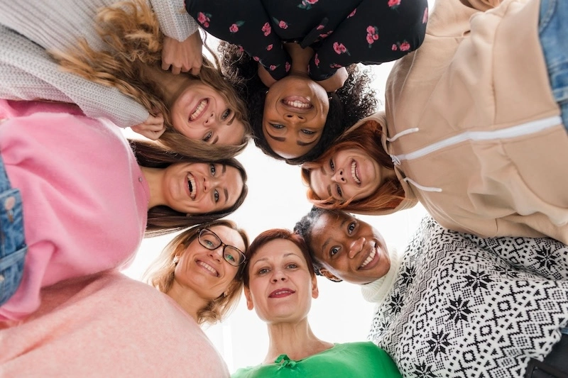 . A group of women gazing up at the camera, displaying expressions of happiness and togetherness.