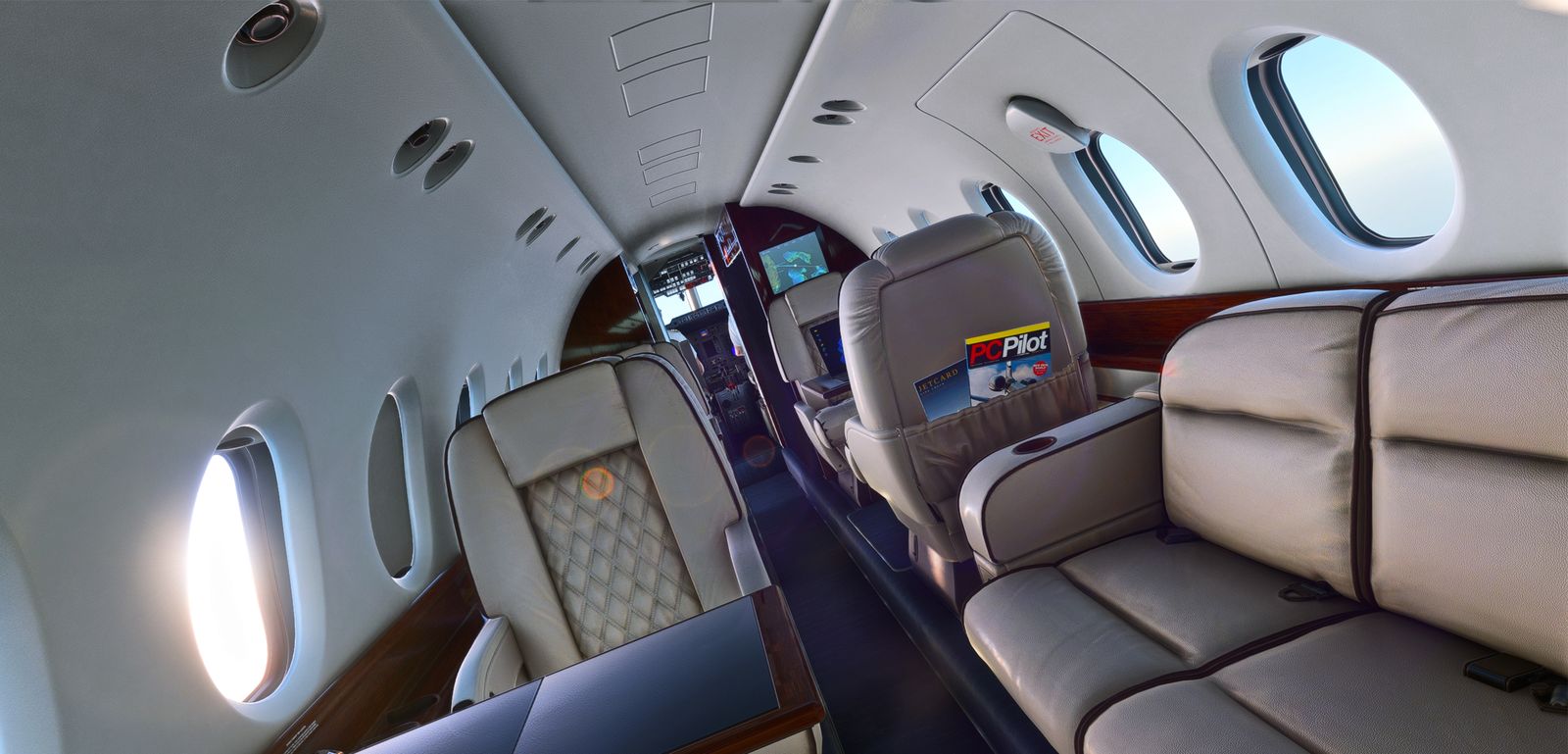 Hawker 800XP passenger cabin with cream seats, a side-facing sofa and oval windows