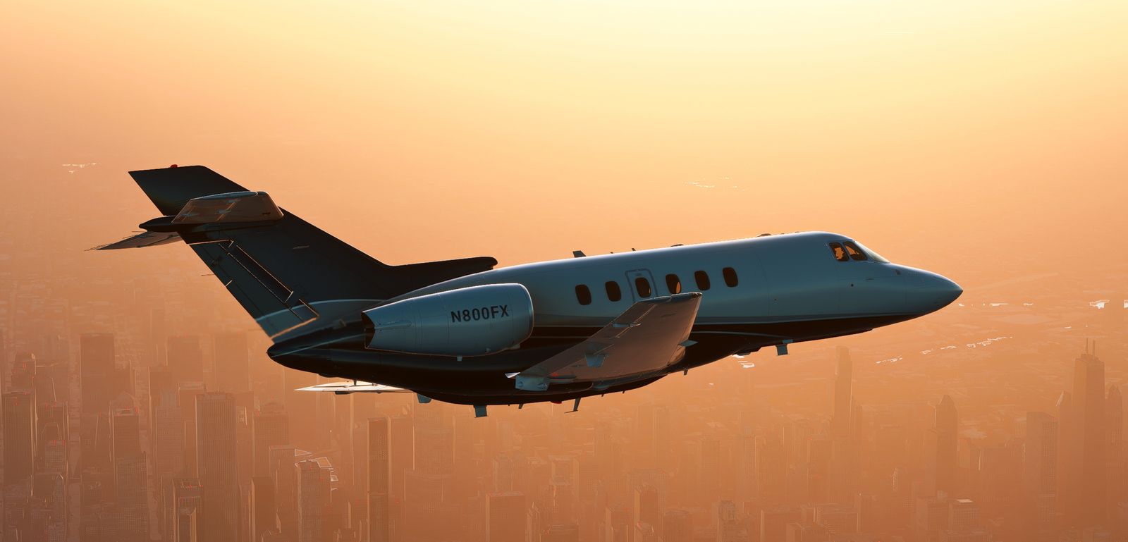 Hawker 800XP in flight against orange evening light above a city