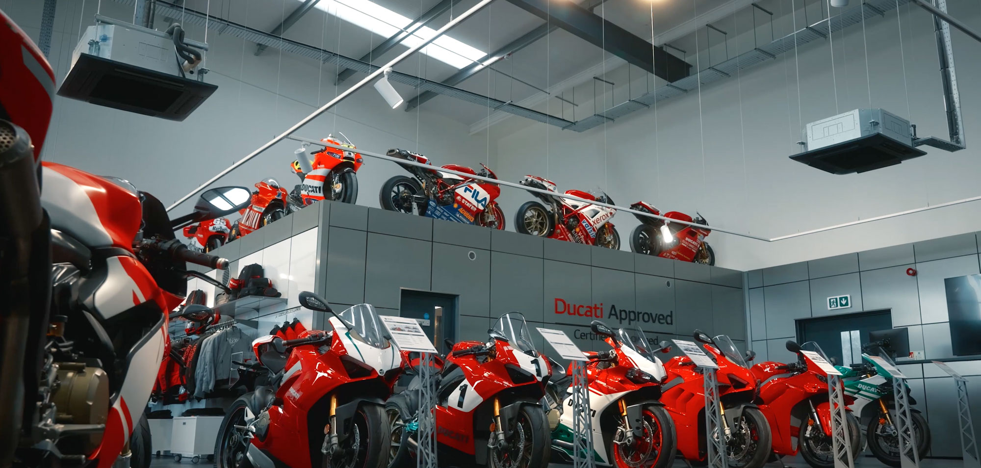 A showroom displaying multiple red motorcycles lined up, with more showcased on overhead platforms.
