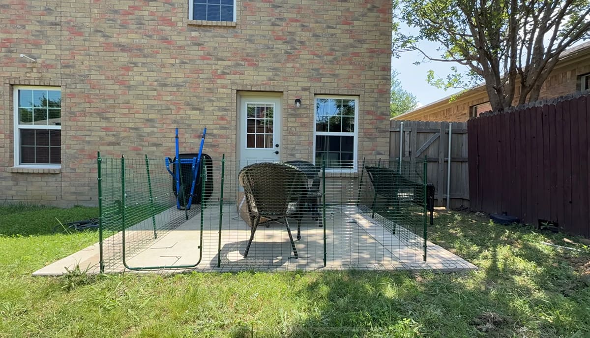 A wire catio from Omlet that is halfway built on a concrete slab.