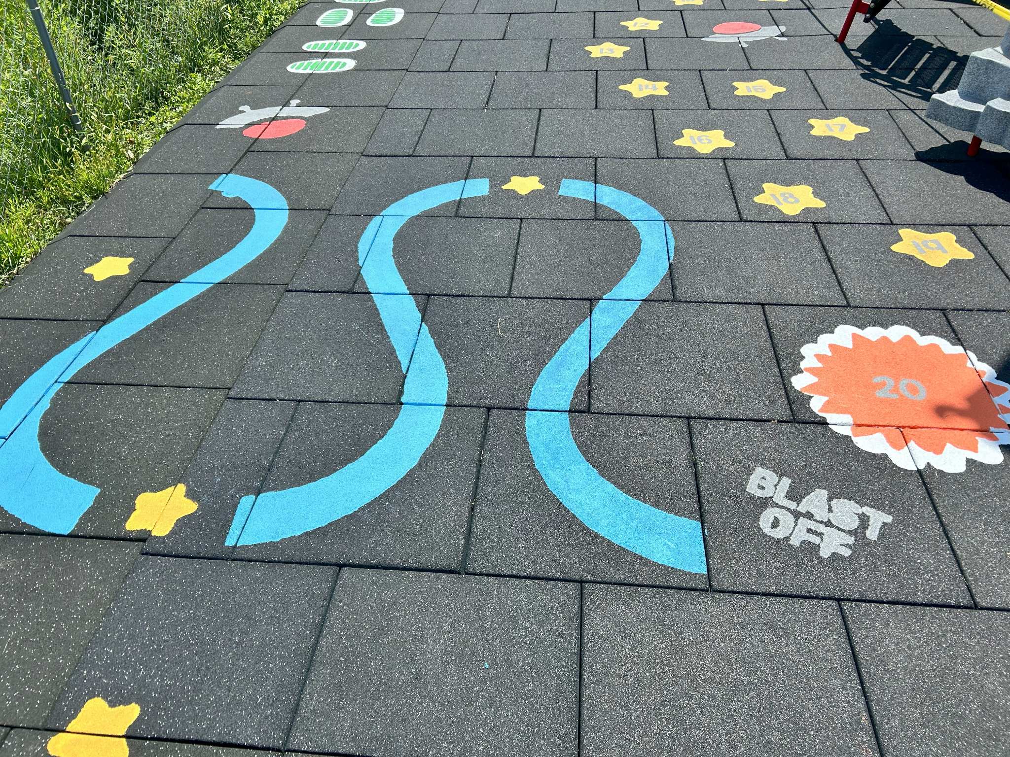 Promotional graphic from Black Hawk County Public Health announcing grant-funded sensory paths to promote children's health in Black Hawk County. The top section includes the agency's logo, name, announces a press release. The center image shows a photo of a colorful outdoor painted path with a winding blue line, yellow stars, yellow stars, a spaceship, an orange circle with "20," and a "BLAST OFF" graphic. Text at the bottom reads: "BLACK HAWK COUNTY PUBLIC HEALTH | Prevent. Promote. Protect."
